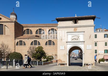 Chioggia, Italie - 3 mars 2025 : Porta Garibaldi et la cathédrale, avec des piétons dans le centre historique de la ville Banque D'Images