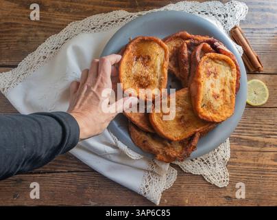 Main humaine ramassant des torrijas, plat typique de Pâques en Espagne Banque D'Images