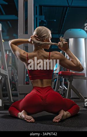 femme avec un physique tonique est engagé dans une routine de remise en forme dans un gymnase contemporain. Elle s'étire et pose pour améliorer sa souplesse et sa force Banque D'Images