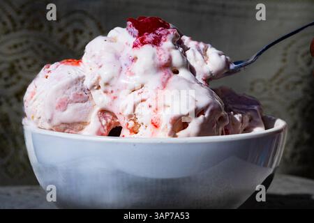 Un bol de crème glacée à la fraise. Le bol est à moitié plein et la crème glacée fond Banque D'Images