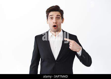 Un homme d'affaires surpris et heureux se faisant remarquer et se réjouissant de bonnes nouvelles, reçoivent une réponse positive, étant choisi ou gagnant, se tenant contre wh Banque D'Images
