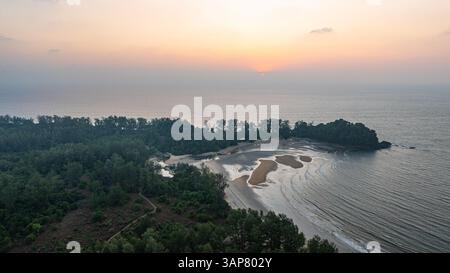 C'est une belle image de coucher de soleil sur l'océan, avec une petite île ou masse terrestre au premier plan. Les teintes dorées du soleil se fondent harmonieusement en t Banque D'Images