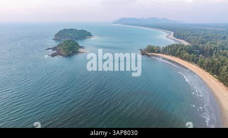 C'est une belle image de coucher de soleil sur l'océan, avec une petite île ou masse terrestre au premier plan. Les teintes dorées du soleil se fondent harmonieusement en t Banque D'Images