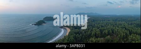 C'est une belle image de coucher de soleil sur l'océan, avec une petite île ou masse terrestre au premier plan. Les teintes dorées du soleil se fondent harmonieusement en t Banque D'Images