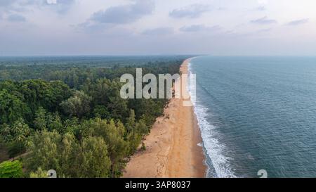 C'est une belle image de coucher de soleil sur l'océan, avec une petite île ou masse terrestre au premier plan. Les teintes dorées du soleil se fondent harmonieusement en t Banque D'Images