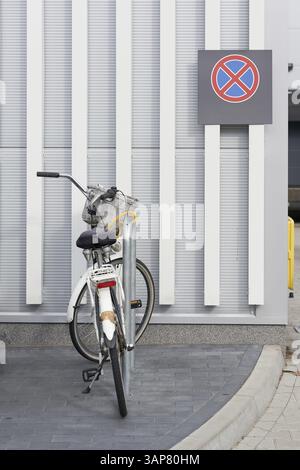 Bicyclette verrouillée dans un supermarché, avec un panneau d'arrêt sur le mur derrière Banque D'Images