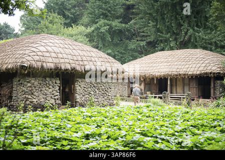 Maisons traditionnelles anciennes kroéennes dans un musée de village folklorique avec un homme marchant entre les deux, Corée du Sud, Asie Banque D'Images