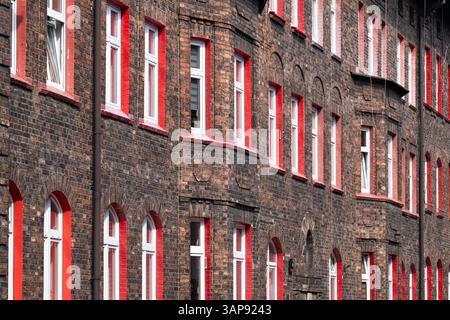 Élévation de la maison d'habitation en briques rouges. Cadres de fenêtre rouges. Lotissement de vieilles ouvrières. Architecture unique. Katowice Nikiszowiec. Pologne Banque D'Images