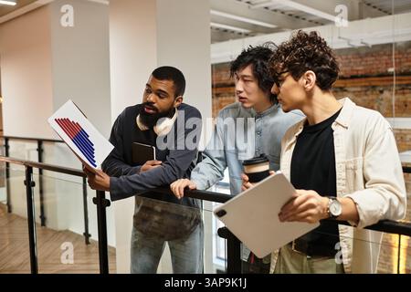 Trois professionnels discutent des plans de projet tout en examinant les documents. Banque D'Images