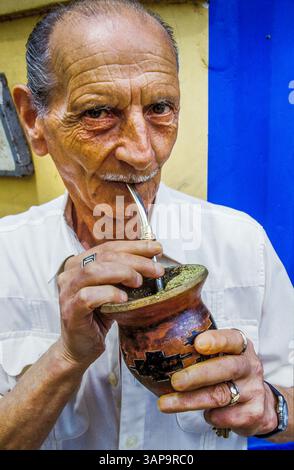 Argentine, Buenos Aires. Homme buvant maté, une boisson traditionnelle sud-américaine à base de plantes infusée riche en caféine avec une paille métallique (bombilla) dans un contenant Banque D'Images