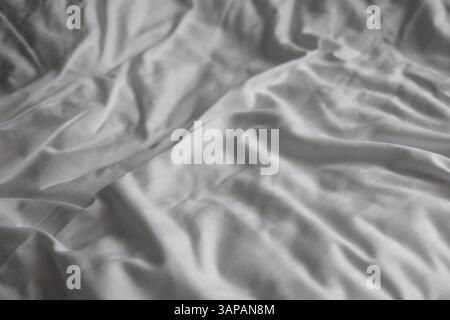 Draps de lit froissés et blancs avec de nombreux plis Banque D'Images