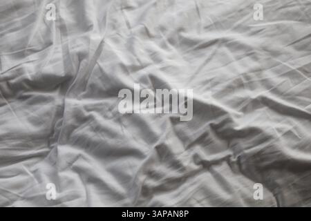 Draps de lit froissés et blancs avec de nombreux plis Banque D'Images