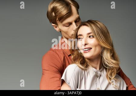 Un jeune couple sourit et partage un moment tendre, mettant en valeur leur mode printanière élégante. Banque D'Images