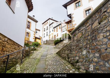 Une rue pavée escarpée et étroite à Lastres bordée de maisons blanches traditionnelles. Lastres, municipalité de Colunga, Asturies, nord de l'Espagne. Banque D'Images
