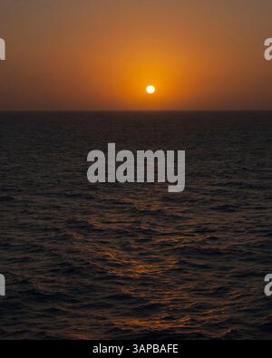 25 janvier 2010 - mer des Caraïbes - la boule géante du soleil remplit le ciel en orange alors qu'il commence à plonger sous l'horizon dans un coucher de soleil spectaculaire sur la mer tropicale des Caraïbes. (Crédit image : © Arnold Drapkin/ZUMAPRESS.com) Banque D'Images
