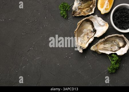 Huîtres savoureuses au citron et au caviar sur fond noir Banque D'Images