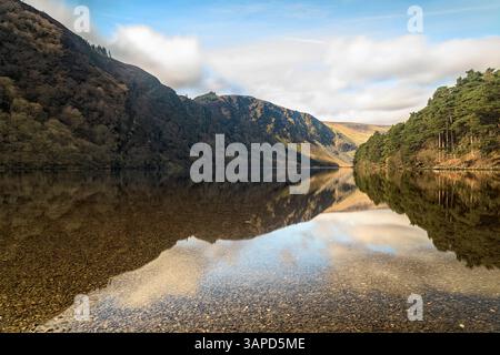 Lac reflétant les pentes de montagne à Glendalough, la beauté tranquille d'une célèbre vallée irlandaise historique. Banque D'Images