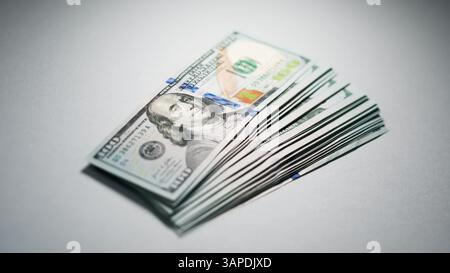 Une vue rapprochée d'une pile de billets de cent dollars positionnés sur un fond neutre. Banque D'Images