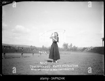 PH036 3941, qui fait partie de la collection Lee Moorhouse, met en scène Jane Bermudy exécutant des tours de corde. Cette photographie historique, conservée dans les bibliothèques de l'Université de l'Oregon, capture un moment de rodéo et de spectacle de cirque. Banque D'Images