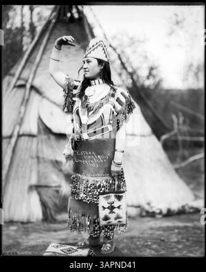 Photographie de Lee Moorhouse montrant Esther Umahollis, une femme tribale Umpqua, en regalia à côté d'un tipi, qui fait partie de la collection des bibliothèques de l'Université de l'Oregon. L'image reflète le patrimoine culturel indigène et les vêtements traditionnels. Banque D'Images