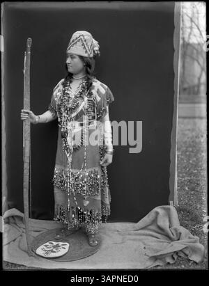 Une photographie de Lee Moorhouse montrant Esther Umahollis, une femme tribale Umpqua, portant divers régalias et tenant des instruments, capturant son héritage culturel et son identité tribale. Banque D'Images
