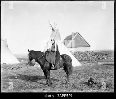Une photographie de Lee Moorhouse montrant une amérindienne à cheval. Cette image historique capture la figure en tenue traditionnelle, mettant en valeur un aspect culturel important de l'époque. Banque D'Images