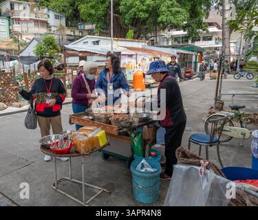 Hong Kong. Chine- 02.27.2025. Touristes achetant des fruits de mer séchés à l'étal d'un villageois dans le village de pêcheurs de Tai O, île de Lantau. Banque D'Images