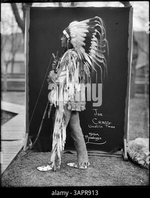 Joe Craig, un Indien Umatilla, est représenté en regalia complet avec un bonnet de guerre, un arc et une flèche, représentant la tenue traditionnelle de guerrier amérindien. Banque D'Images