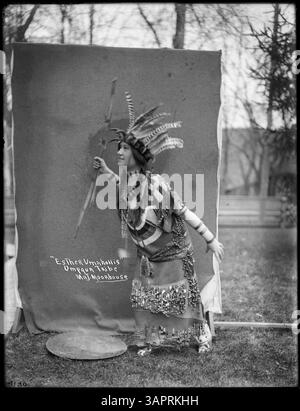 Une photographie similaire à 43081, montrant Esther Umahollis, une femme tribale Umpqua, portant des regalia traditionnels et tenant des instruments cérémoniels. L'image offre un aperçu de la tenue vestimentaire et des pratiques culturelles du peuple Umpqua dans l'Oregon. Banque D'Images