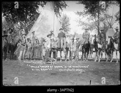 Photographie en noir et blanc d'individus posant devant un tipi, une demeure amérindienne traditionnelle. L'image capture un moment d'importance culturelle, avec le tipi en arrière-plan et les gens habillés en tenue d'époque. Banque D'Images