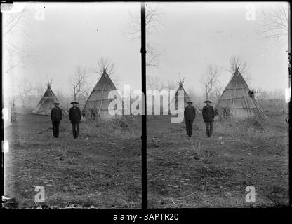 Cette photographie de Lee Moorhouse capture deux hommes debout près de deux tipis. L'image est présentée en stéréo, montrant l'importance culturelle des habitations amérindiennes et des individus sur la photo. Banque D'Images