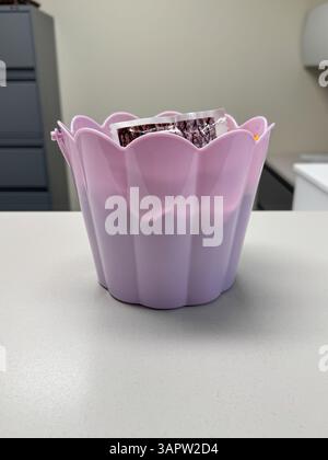 Chocolats de Pâques colorés dans un bol brillant en forme de fleur pourpre sur un fond blanc. Assortiment de bonbons festifs célébrations printanières parfaites, vacances Banque D'Images