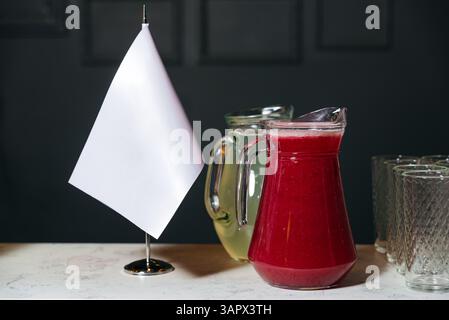 Deux pichets en verre remplis de jus de baies rouges et d'agrumes placés sur un comptoir avec des verres vides à proximité. Banque D'Images