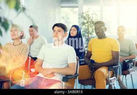 Guy Teenager écoute la conférence tout en étant assis sur la chaise Banque D'Images