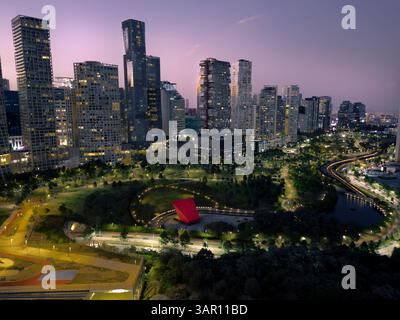 Photo aérienne longue exposition du quartier de Santa Fe à Mexico, montrant des gratte-ciel illuminés et le luxuriant parc la Mexicana au crépuscule. Banque D'Images