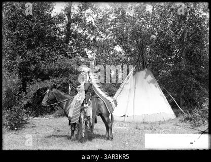 Une photographie de la collection Lee Moorhouse montrant un homme amérindien en costume traditionnel à cheval. Banque D'Images