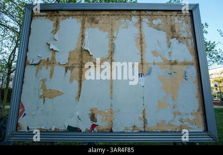 Panneau d'affichage endommagé et vide avec des restes de papier déchiré à Berlin, symbolisant la décomposition des médias, le changement urbain et la messagerie publique. Banque D'Images