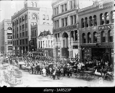 Cette photographie historique montre une grande foule rassemblée devant le bâtiment du Journal sur la 4e rue, Minneapolis, en attente des résultats des élections. Le wagon A. Booth Packing Company est visible en bas à droite, et les commerces de l'autre côté de la rue sont nommés. Notamment, l'horloge devant le Pioneer Fuel Co. manque de visage. Banque D'Images