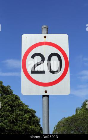 20 km h signe de limite de vitesse avec un ciel bleu et des arbres en arrière-plan Banque D'Images