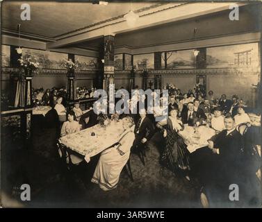 Une photographie capturant une fête au café Nankin, mettant en scène un homme barbu assis à une table au premier plan gauche. L'événement est documenté par Hennepin County Library. Banque D'Images