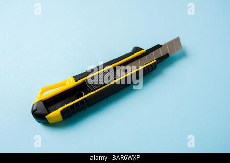 Vue de dessus du couteau utilitaire jaune et noir sur fond bleu Banque D'Images