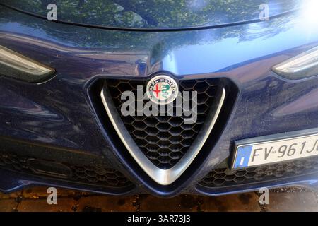 Cremona, Italie 15 avril 2025 Alfa Romeo Stelvio Veloce affichant une calandre triangulaire distinctive, logo de la marque contre la surface réfléchissante reflétant sur Banque D'Images