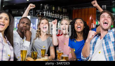 Image de confettis en or tombant sur un groupe heureux et diversifié d'amis buvant dans le bar Banque D'Images