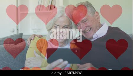 Image d'icônes de cœur de médias sociaux sur un couple de personnes âgées utilisant un smartphone Banque D'Images