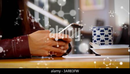 Image de molécules flottant sur les mains d'une femme caucsienne utilisant un smartphone Banque D'Images