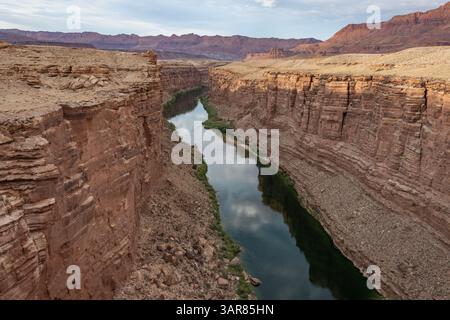 Une rivière sereine coule doucement à travers un canyon magnifique, reflétant les formations rocheuses colorées et le ciel crépusculaire. Le paysage met en valeur la beauté de nat Banque D'Images