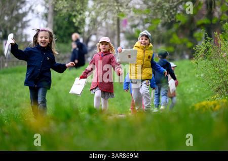 Weimar, Allemagne. 17 avril 2025. Les enfants du 'KulturKindergarten am Goethepark' prennent part à la chasse aux œufs de lapin traditionnelle autour du jardin de Goethe à Weimar. Goethe lui-même a initié l'amusement pour enfants en 1777 - d'abord pour les enfants d'amis, plus tard pour son fils August, ses amis et ses petits-enfants. La Klassik Stiftung Weimar perpétue cette tradition et invite les enfants à la chasse annuelle aux œufs de lapin de Goethe dans la prairie autour du jardin de Goethe. Les œufs de Pâques peuvent être recherchés, trouvés et mangés là-bas. Crédit : Hendrik Schmidt/dpa/Alamy Live News Banque D'Images