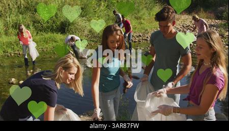 Image de cœurs verts sur divers groupes heureux ramassant des ordures dans la campagne Banque D'Images