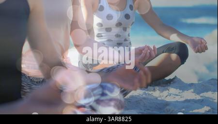 Image de taches lumineuses sur diverses femmes pratiquant le yoga et méditant à la plage Banque D'Images