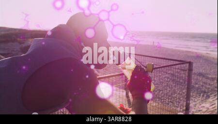 Structures moléculaires brillantes flottant contre l'homme afro-américain apte à boire de l'eau près de la plage Banque D'Images